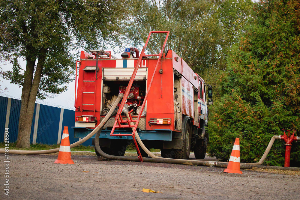 Obraz premium Fire truck pumping water from a hydrant in a tranquil neighborhood during a quiet afternoon