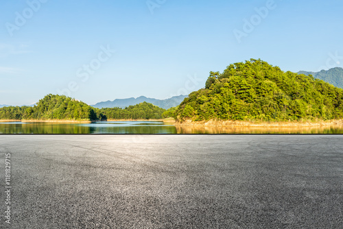 Obraz na płótnie Asphalt road square and lake water with green mountain nature landscape under blue sky. Outdoor asphalt parking lot. w salonie