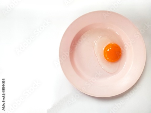 Duck egg yolk on a pink plate on a white background. photo