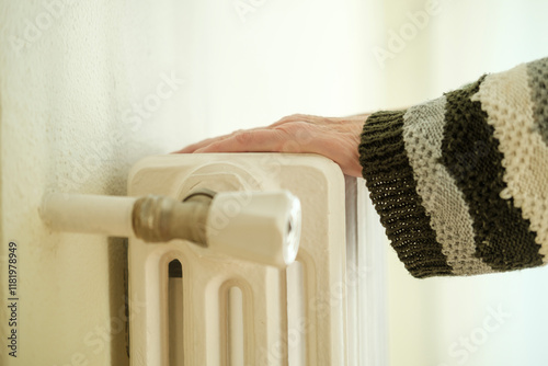 Senior woman checking temperature of home heating radiator