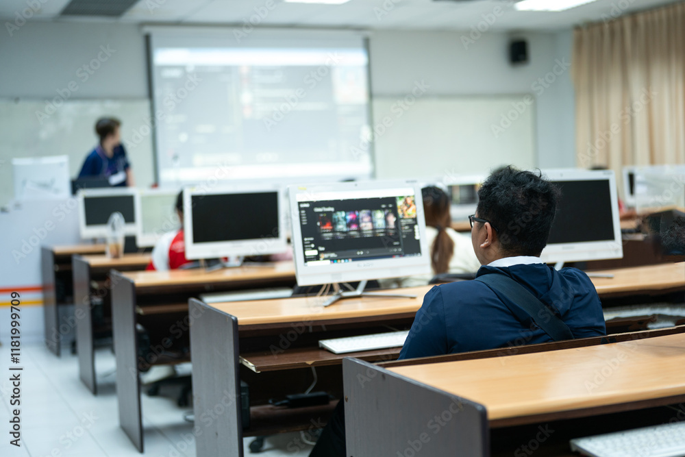 Students are seated at desks using desktop computers in a classroom, focusing on their tasks in a learning environment equipped with technology. Students are seated at desks using desktop computers in a classroom, focusing on their tasks in a learning environment equipped with technology.