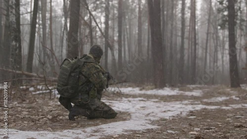 Special forces in forest. Armed reconnaissance soldier in winter forest. Infantryman makes his way through a snowy forest. Soldier in Snow Covered Terrain Training for Cold Weather Military Maneuvers.