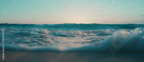 Peaceful sandy shore meets calm ocean waters under a clear sky at sunset