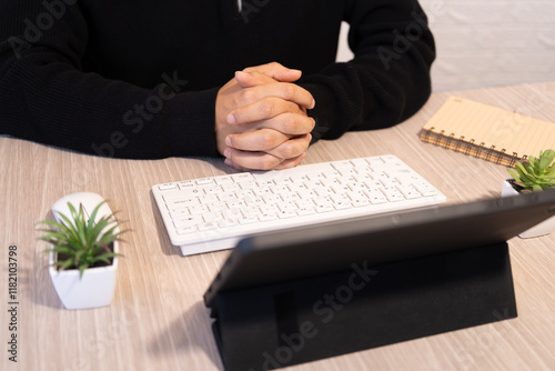 Businessman waiting with fingers crossed in front of his laptop