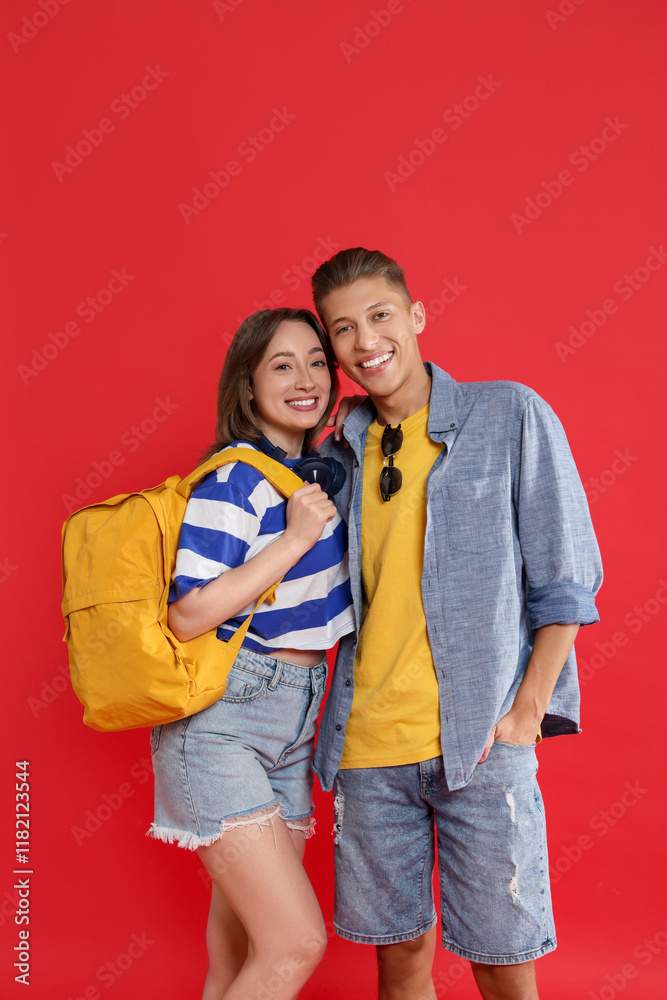 Traveller with backpack. Happy young woman and man on red background Traveller with backpack. Happy young woman and man on red background