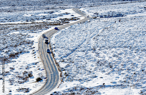 Snowy road with cars driving along a twisty highway in a wilderness location. Hazardous winter driving conditions. Icy roads and accidents. photo