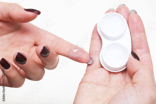 Woman handling a contact lens with care. Cleaning process using lens liquid. Contact lens contanier and close-up of lens on fingertip. Vision care and hygiene. photo