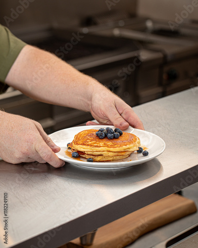 Chef making pancakes wuth blueberries in the cafe photo