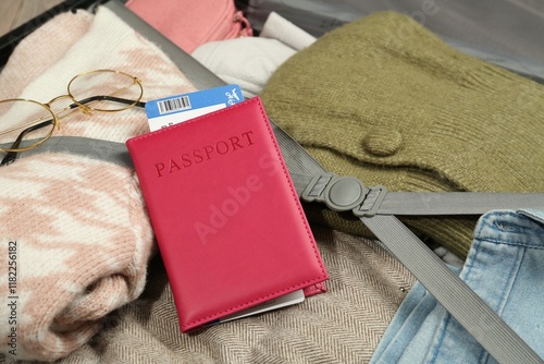 Passport with ticket on packed suitcase, closeup