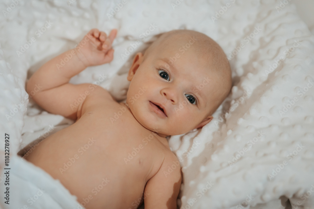 A baby is laying on a white blanket with its eyes closed. The baby is smiling and he is content A baby is laying on a white blanket with its eyes closed. The baby is smiling and he is content