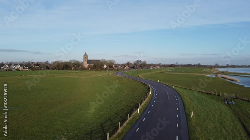 Zalk, the Netherlands - January 8th 2025: Aerial footage of the Dutch village Zalk. The drone is taking of from the dyke and moving towards the Sint Nicolaas church.