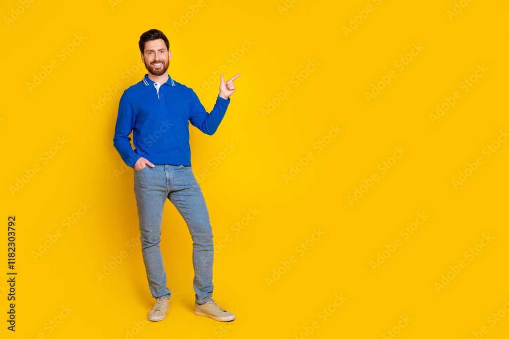 Full body photo of attractive young man point empty space dressed stylish blue clothes isolated on yellow color background