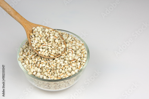 Wood spoon of Job's tears white background.
Adlay or millet in Wooden ladle and 
glass bowl.   Scientific name is Cox lacrima job.
top view.