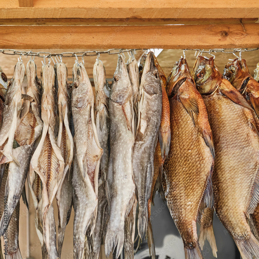 Obraz premium Row of dried fish hanging on hooks on outdoor rural market