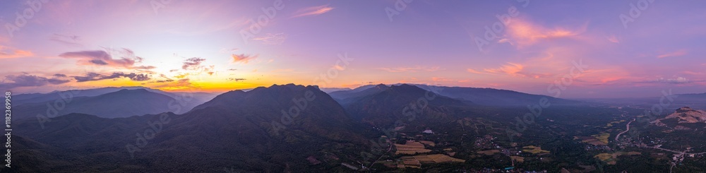 Obraz premium A breathtaking view of a colorful sunset over layered mountain silhouettes, with warm hues of orange, pink, and blue blending seamlessly across the sky.