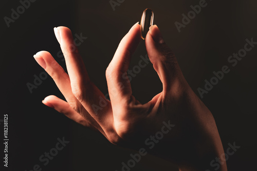 Hand holding a golden capsule representing the benefits of omega 3 for health and wellness