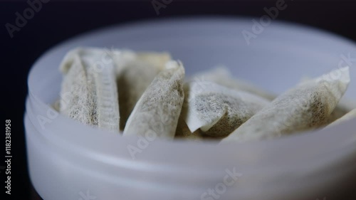 Snus nicotine tobacco close up, pack of tobacco for gum. unhealthy addiction. Man opening box with snus and taking one.  photo