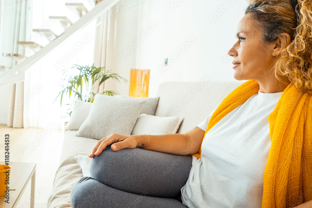 A fifty-year-old woman relaxing alone in her living room at night, sitting on her sofa in silence, contemplating her thoughts, and embracing a mindful moment of introspection and personal growth A fifty-year-old woman relaxing alone in her living room at night, sitting on her sofa in silence, contemplating her thoughts, and embracing a mindful moment of introspection and personal growth