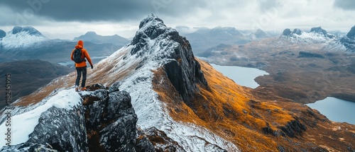 Hiker on snowy peak, overlooking autumnal valley