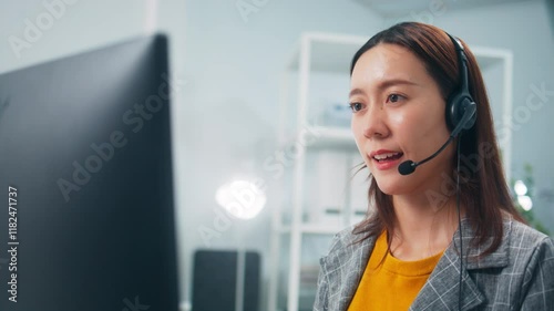 Professional Asian Female IT specialist engages with a customer, using headset and computer, talking with client instructions for solving technical problems sit at desk in modern call center office.