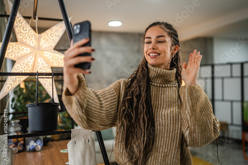 young woman talk and wave on video call via mobile phone photo