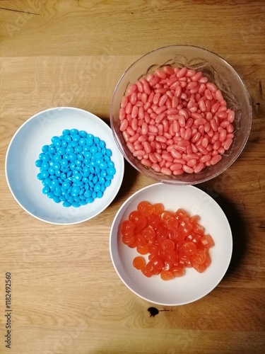 Blue dragee, chocolate covered nuts and sweet candy in the white plates 