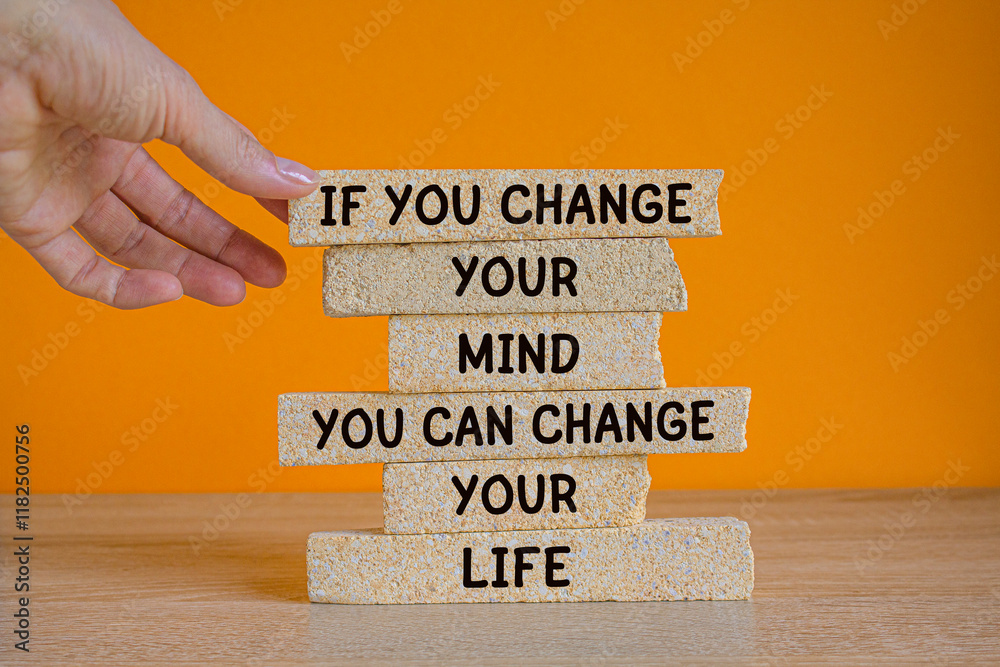 If you change your mind you can change your life. Words on brick blocks on beautiful orange background. Motivational quote to create future. Businessman hand.