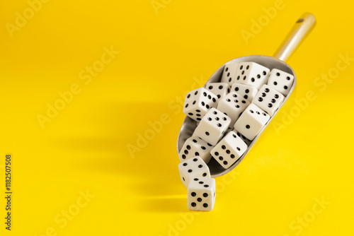 White dice spilling from a metallic scoop on a bright yellow background, symbolizing chance, gambling, and gambling addiction risks. photo