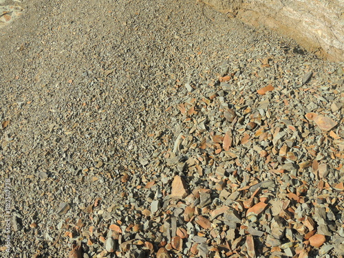 texture of small sharp stone, crumbled copper-colored rock that has rolled down a mountain in bulk, stone chips scattered on a natural slope of a cliff, small fraction of crushed stone photo