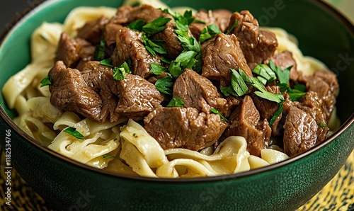 Traditional Kazakh dish Beshbarmak served in a green bowl with tender meat and noodles garnished with parsley photo