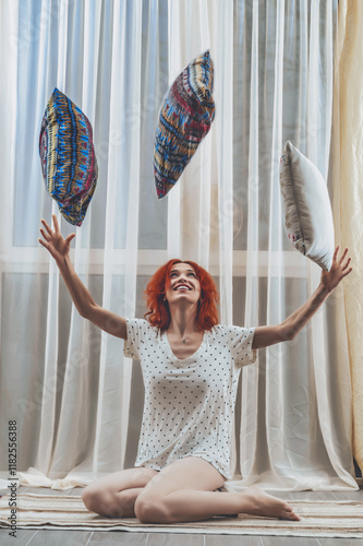 Woman sits on the floor in a room, throws pillows up photo