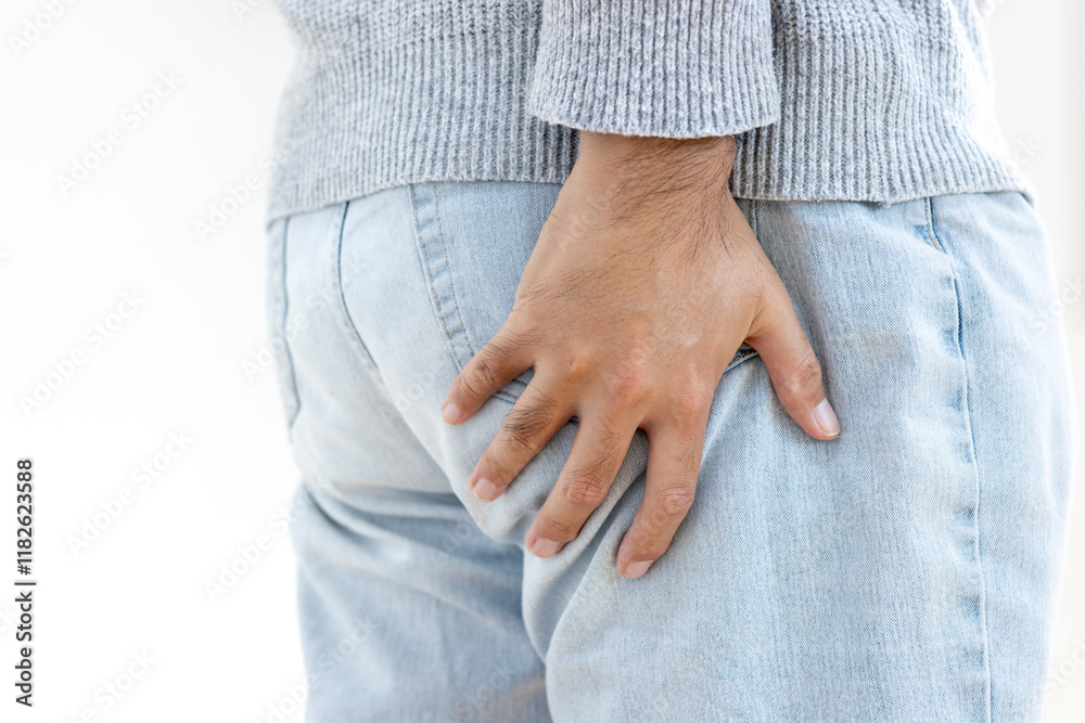 お尻を押さえるセーターを着た男性(30代、日本人、顔無し)