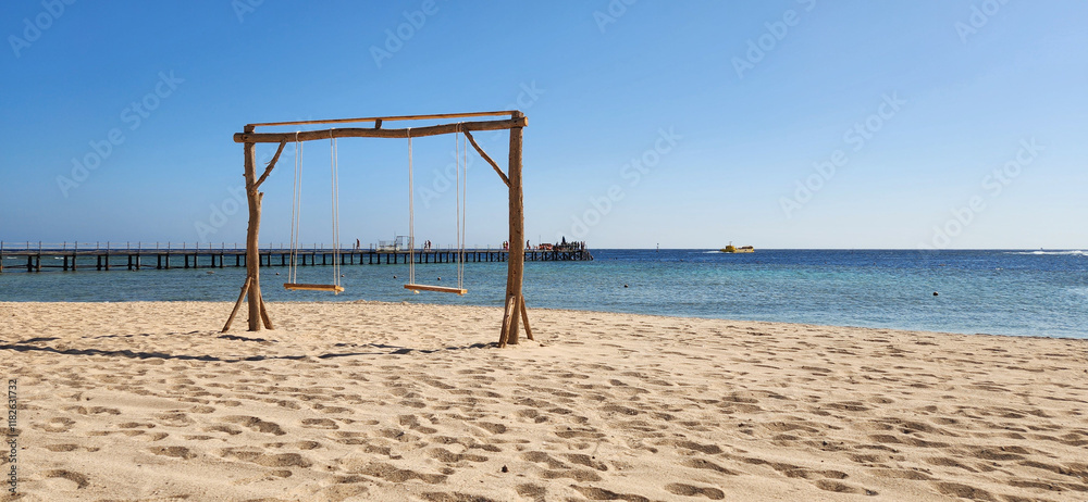 Seaside Wooden Swing on Sandy Beach with Ocean View Under Clear Blue Sky Seaside Wooden Swing on Sandy Beach with Ocean View Under Clear Blue Sky
