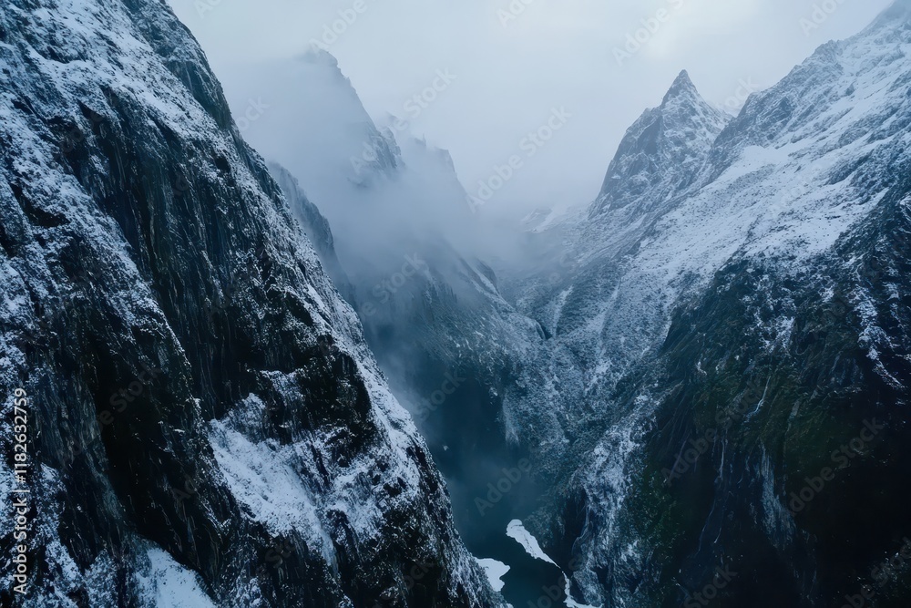 Obraz premium Majestic snow-covered mountains shrouded in mist create an enchanting landscape at dawn in New Zealand's fjords