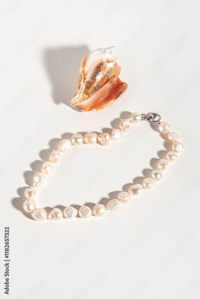 Necklace made of natural cultured pearls. Beads and seashell on white background. Pink pearls Necklace made of natural cultured pearls. Beads and seashell on white background. Pink pearls