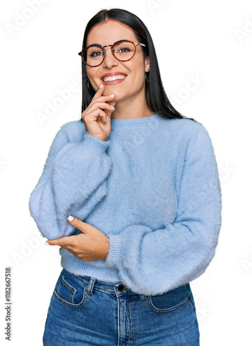 Young hispanic woman wearing casual clothes and glasses looking confident at the camera with smile with crossed arms and hand raised on chin. thinking positive. photo