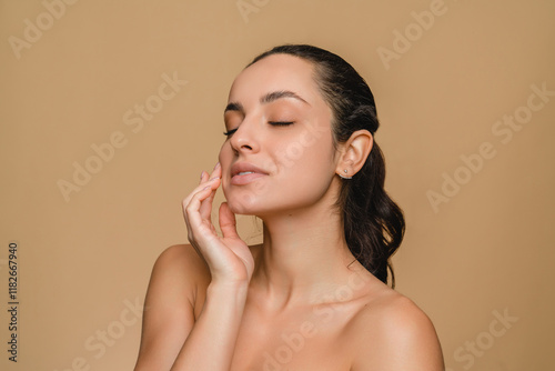 Close up portrait of beauty model young woman with closed eyes clean perfect skin with natural nude make up posing isolated over beige background . Spa, skincare and wellness concept .