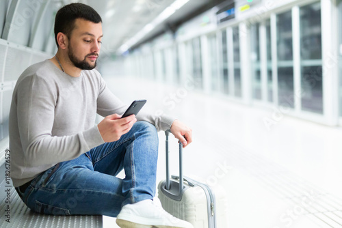 Male passenger in casual clothing reading his mobile phone in subway photo