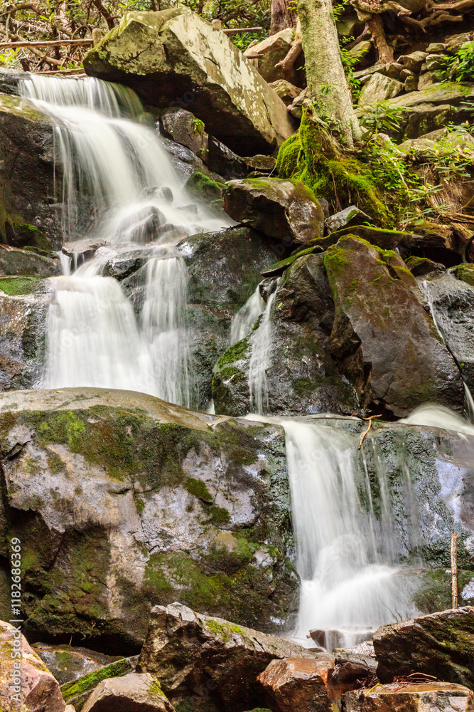 A waterfall is flowing down a rocky cliff A waterfall is flowing down a rocky cliff