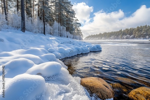 Calm water flows beside picturesque snowy shores, expertly covered in frost under a bright blue sky. The serene landscape reflects the tranquility of winter's embrace photo