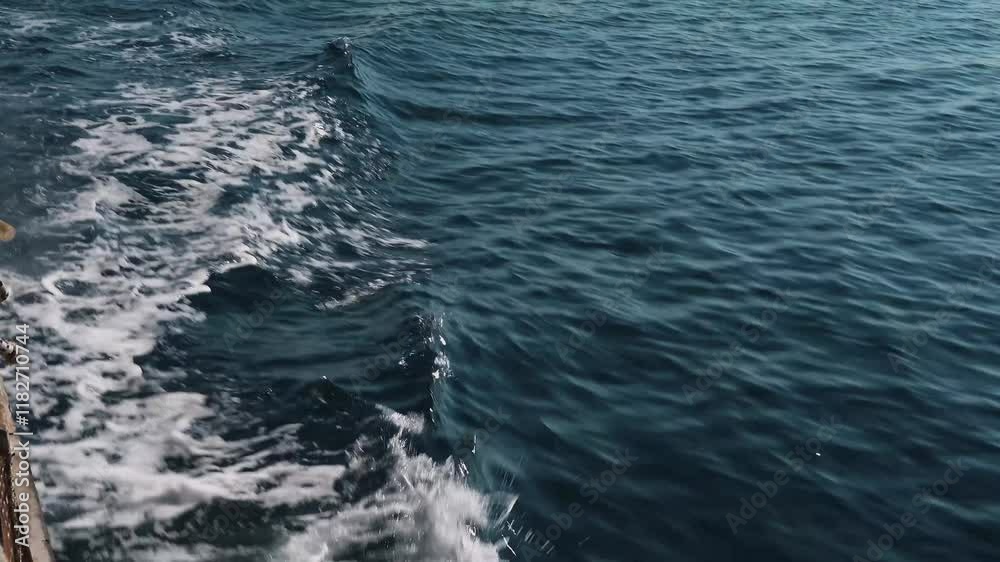 blue waves of water crash against the side of the ship