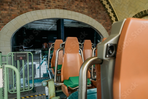 An amusement park attraction without people. Roller coaster seats, amusement train in the parking lot, on maintenance. No one