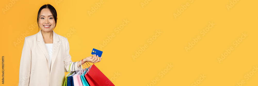 Smiling millennial chinese woman with shopping bags, credit card, enjoy sale, isolated on orange studio background. Finance for purchases, money recommendation for shopaholic Smiling millennial chinese woman with shopping bags, credit card, enjoy sale, isolated on orange studio background. Finance for purchases, money recommendation for shopaholic