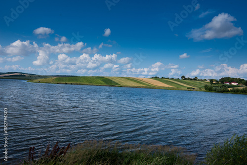A panoramic view of the reservoir, hills in lines with fields of green grass,...