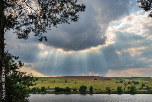 The sun's rays break through the dramatic clouds above the river