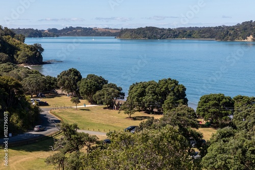 Picnic spot overlooking the bay. People relax on the grassy area, enjoying the sunny day. Beautiful scenery. Sullivans Bay, Warkworth, Auckland, New Zealand photo