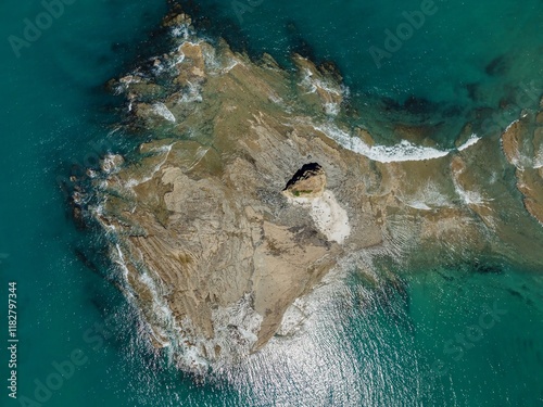 High-angle view of a rocky islet, turquoise water, and waves. Coastal beauty. Pudding Island, Mahurangi West, Auckland, New Zealand photo