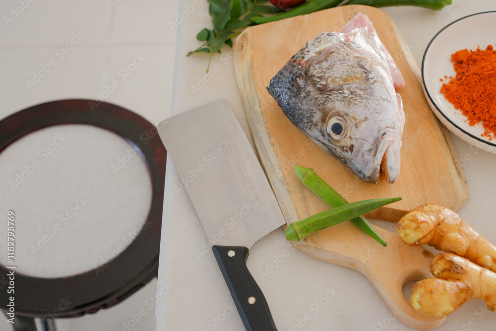 Fresh snapper fish on a wooden cutting board in a kitchen with a knife nearby