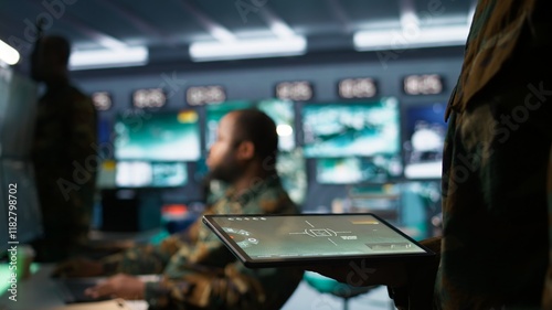 Army operative using tablet in command center housing operational missile defense system designed to intercept ballistic rockets. Close up of expert using tracking software on device, camera B photo