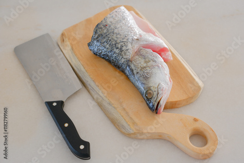 Obraz na płótnie Fresh snapper fish on a wooden cutting board in a kitchen with a knife nearby w salonie